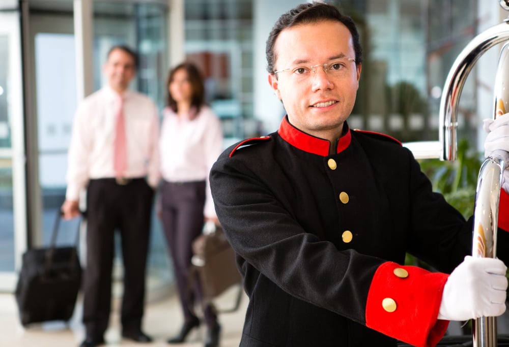 Hotel bellboy carrying the luggage of  a business couple